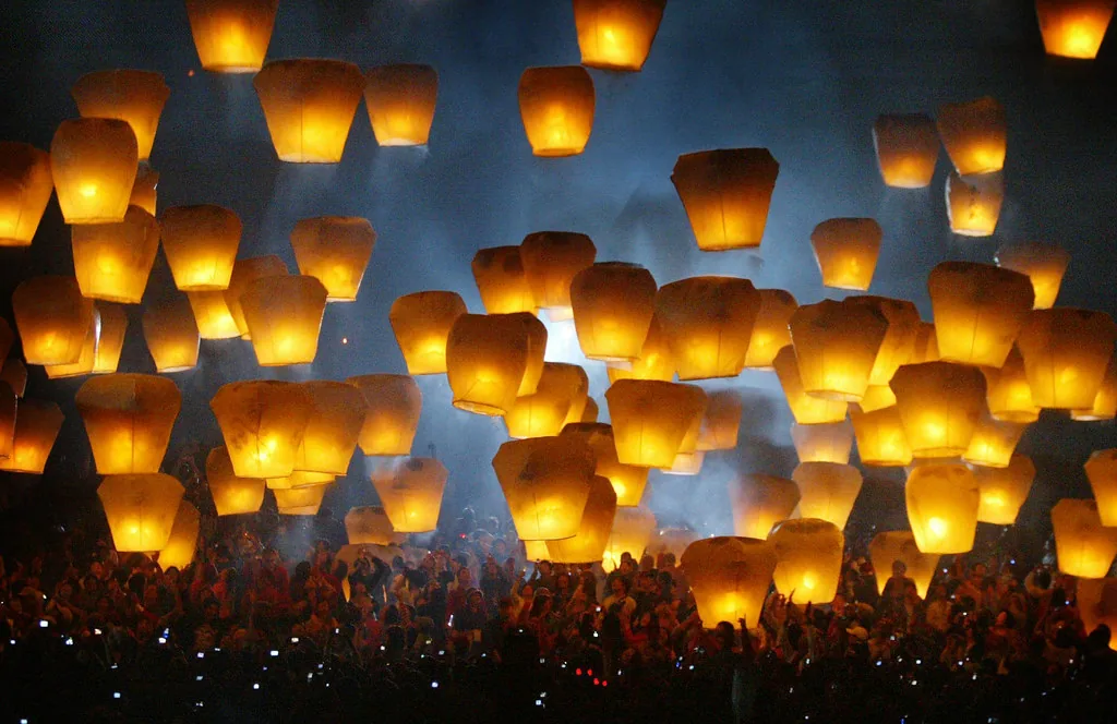 밤하늘로 떠오르는 수많은 소원 풍등과 이를 올려다보는 사람들 — 칠석 소원빌기를 떠올리게 하는 이미지