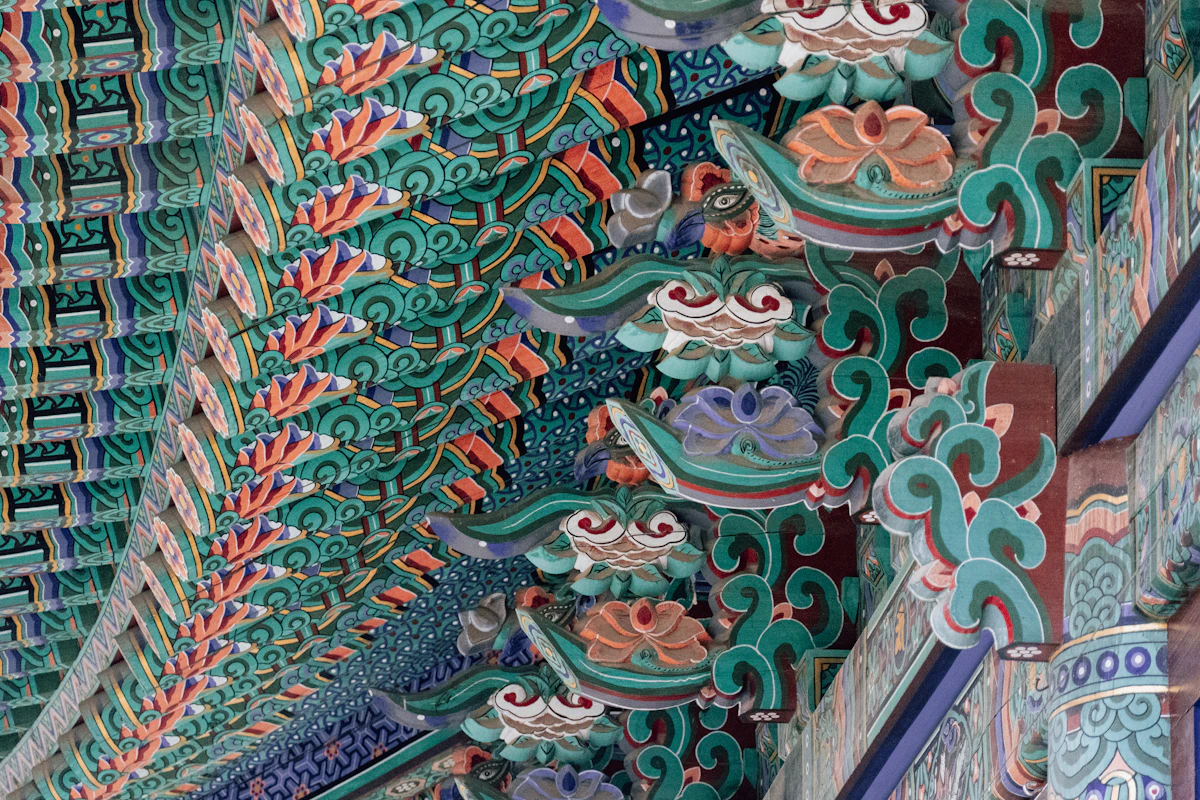 청록과 붉은색이 어우러진 한국 전통 사찰 처마의 단청 무늬로 전통 개운 문화의 분위기를 담은 이미지