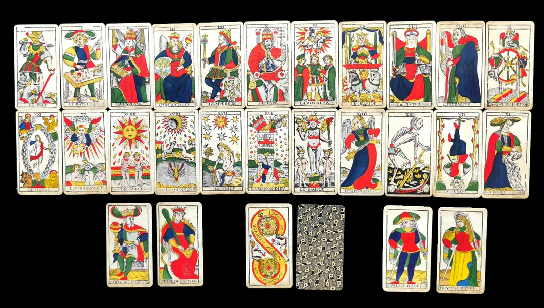 마르세유 스타일 전통 타로 카드 한 벌이 검은 배경에 가지런히 늘어놓인 모습, 마르세유와 토트 같은 전통 덱의 고전적 분위기를 보여 주는 이미지